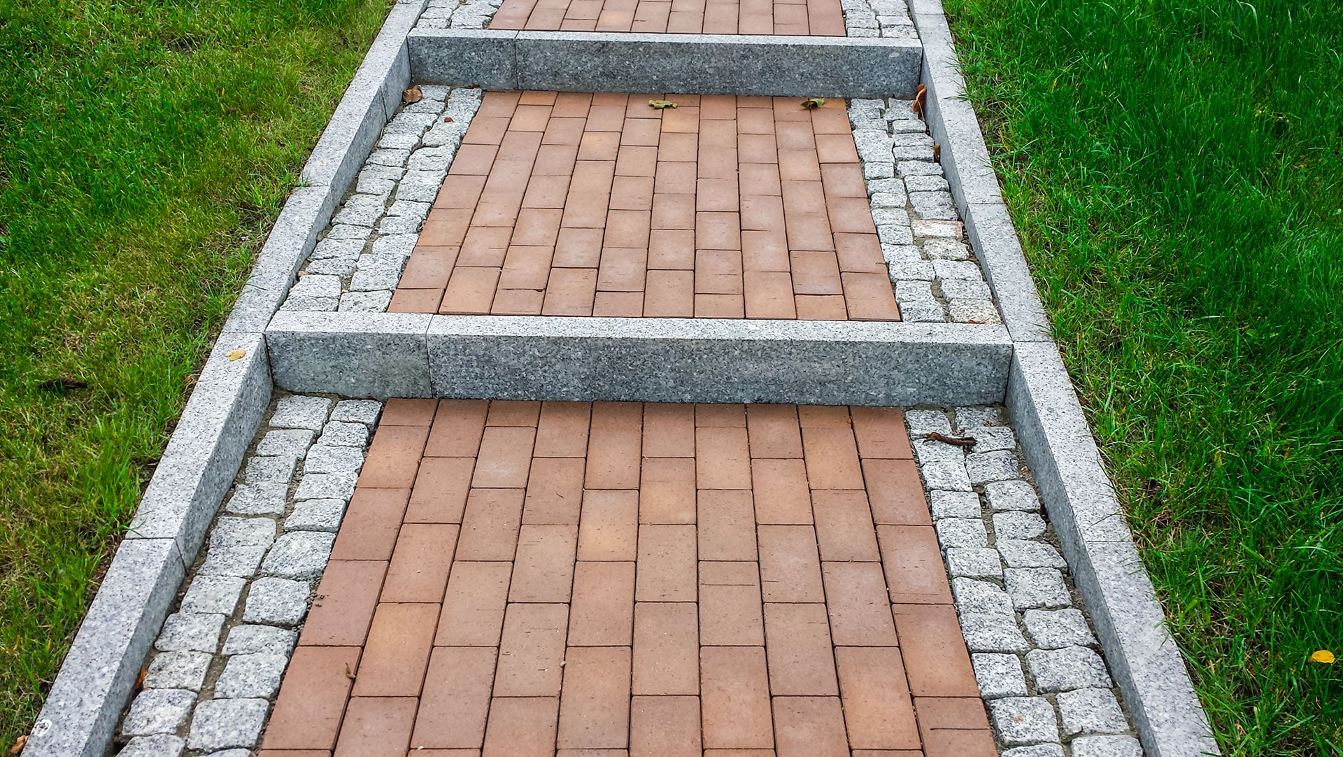 Stairs with red gray cobblestones, among the grass